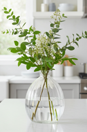Clear vase with greenery on a kitchen counter